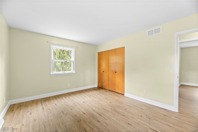 unfurnished bedroom featuring light wood-type flooring and a closet