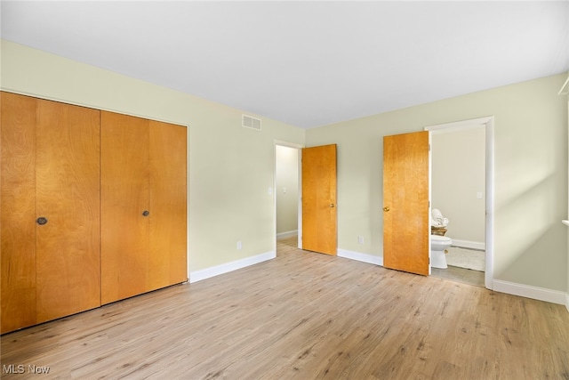 unfurnished bedroom featuring a closet, ensuite bathroom, and light hardwood / wood-style flooring