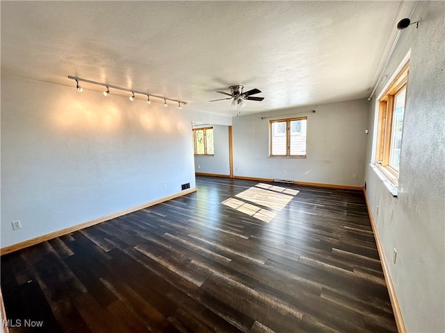 spare room featuring a baseboard radiator, dark hardwood / wood-style flooring, rail lighting, and ceiling fan