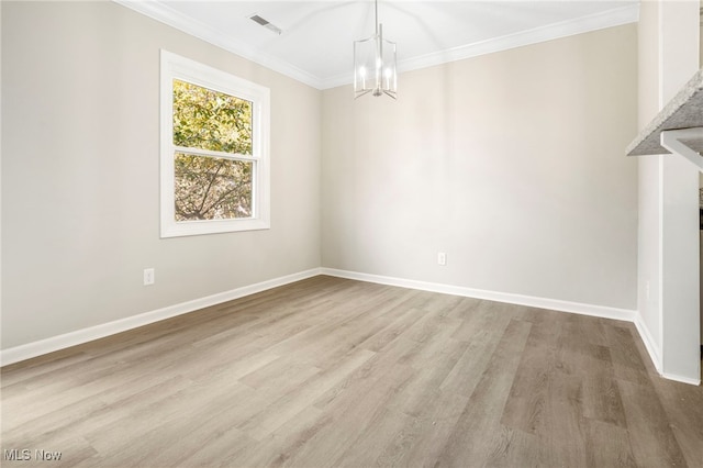 spare room with an inviting chandelier, hardwood / wood-style flooring, and crown molding