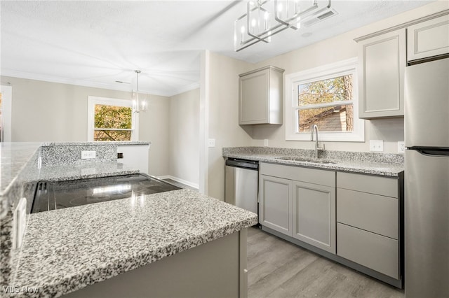 kitchen featuring sink, appliances with stainless steel finishes, decorative light fixtures, gray cabinetry, and light wood-type flooring