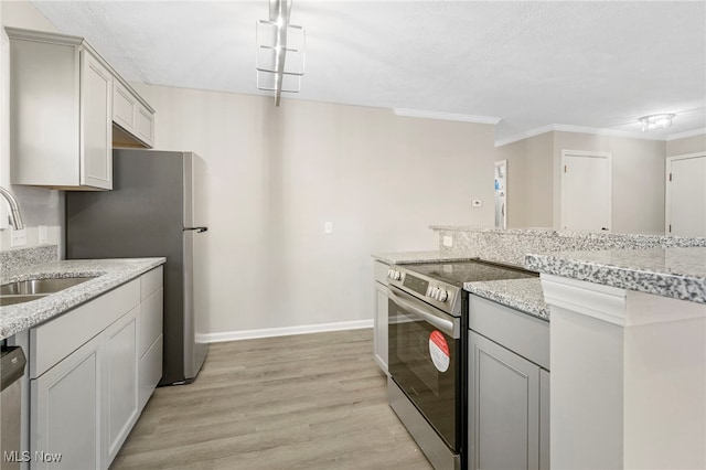 kitchen featuring stainless steel appliances, sink, light stone countertops, crown molding, and light wood-type flooring