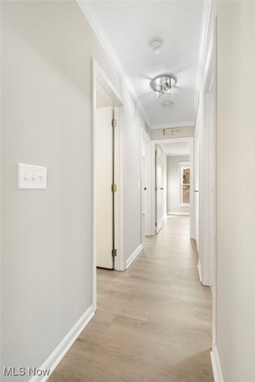 hallway with light wood-type flooring and ornamental molding