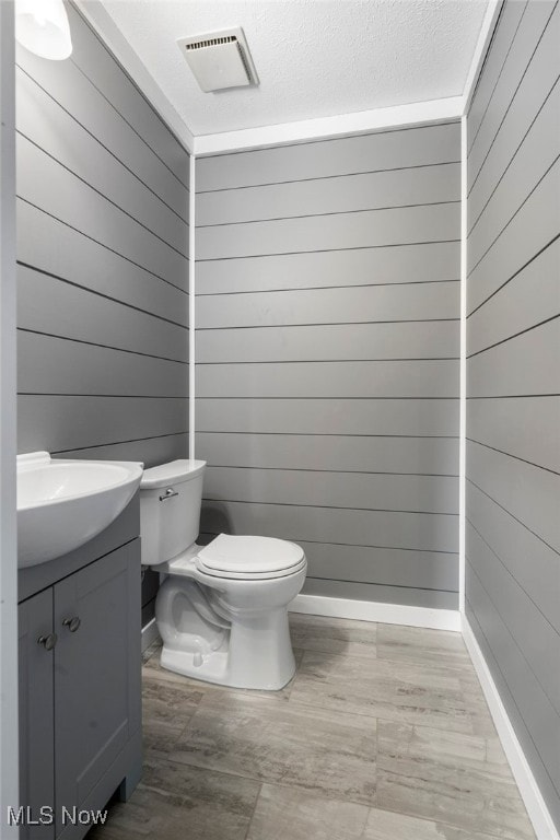 bathroom featuring wood walls and toilet