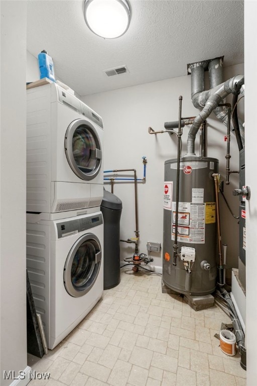 laundry area with stacked washer and clothes dryer, a textured ceiling, and gas water heater