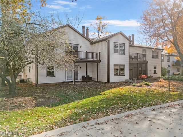 rear view of property featuring a wooden deck and a lawn