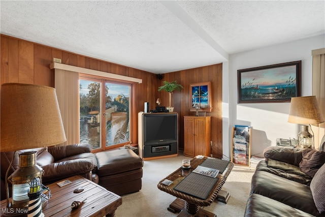 carpeted living room featuring a textured ceiling and wooden walls