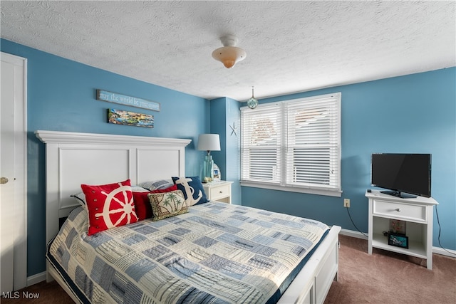 bedroom with a textured ceiling and dark carpet