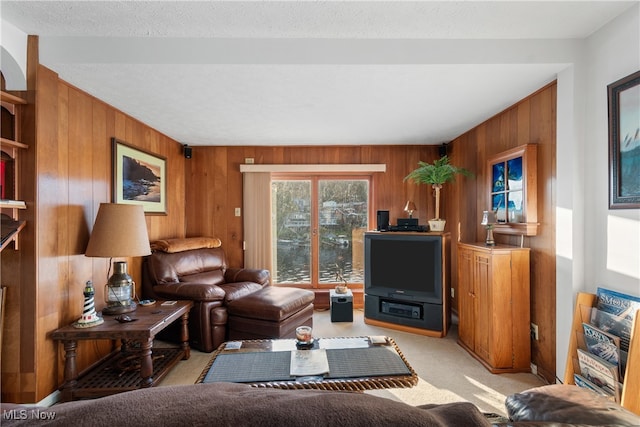 carpeted living room with wooden walls and a textured ceiling