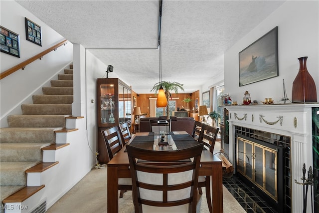 dining space with a tiled fireplace, carpet, and a textured ceiling