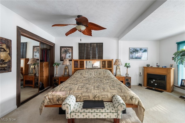 bedroom with a closet, carpet, a textured ceiling, and ceiling fan