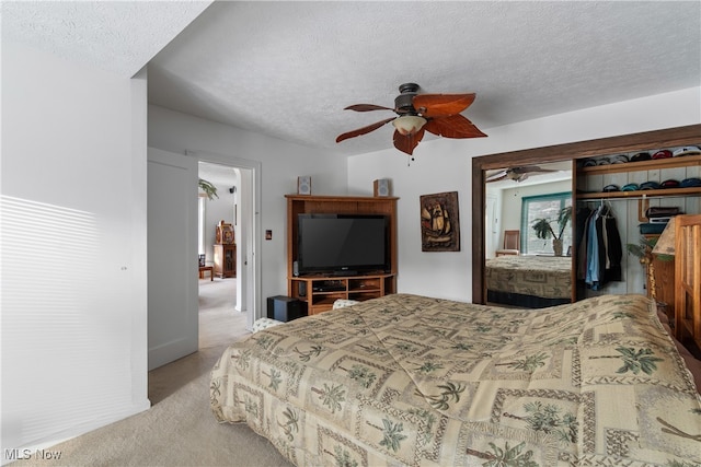 bedroom with light carpet, a textured ceiling, ceiling fan, and a closet