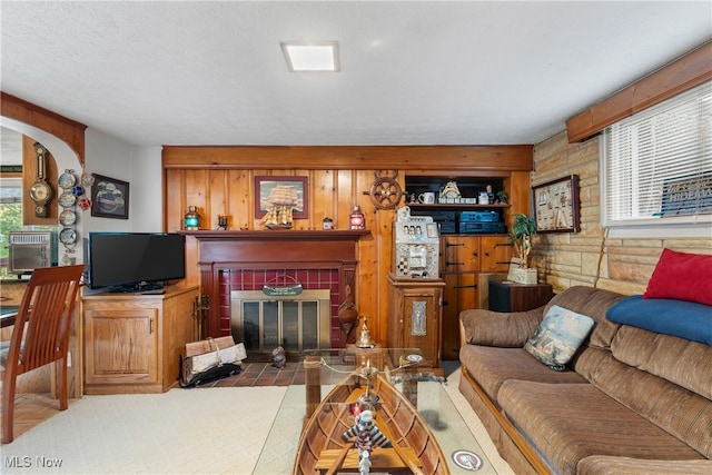 living room featuring a tiled fireplace, wooden walls, a textured ceiling, and a healthy amount of sunlight