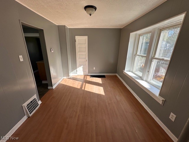 spare room featuring a textured ceiling and dark hardwood / wood-style floors