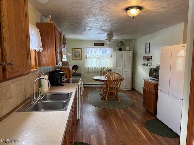 kitchen with decorative backsplash, stove, sink, white fridge, and dark hardwood / wood-style floors