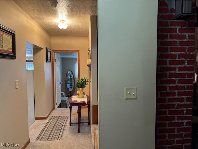 corridor with light colored carpet and a textured ceiling