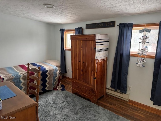 bedroom featuring baseboard heating, multiple windows, dark wood-type flooring, and a textured ceiling