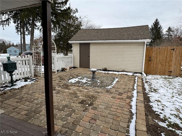 snow covered patio with a storage unit