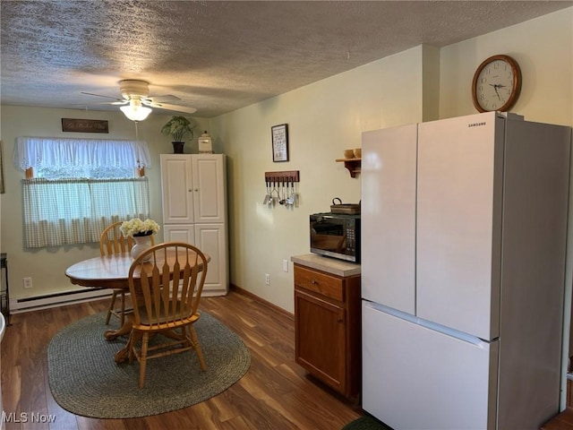 dining room with a textured ceiling, dark hardwood / wood-style floors, a baseboard radiator, and ceiling fan