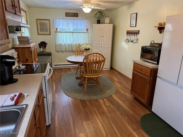 kitchen with sink, a baseboard radiator, white refrigerator, stove, and hardwood / wood-style flooring