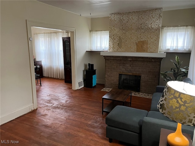 living room with a brick fireplace and dark hardwood / wood-style floors