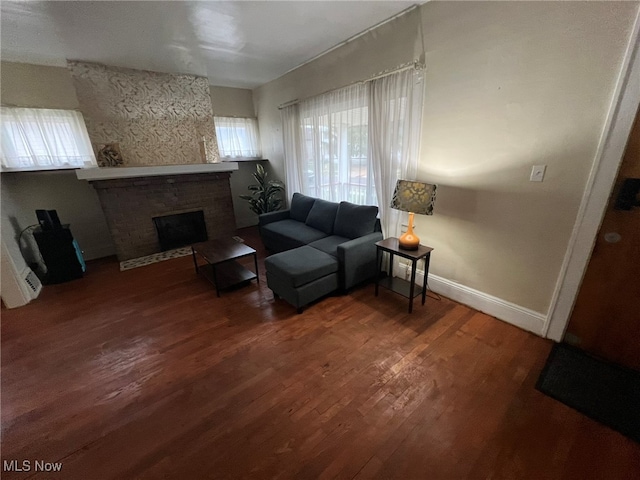 living room with dark hardwood / wood-style flooring and a brick fireplace