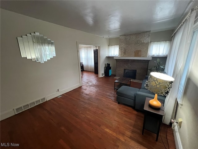 living room with a brick fireplace and dark hardwood / wood-style floors