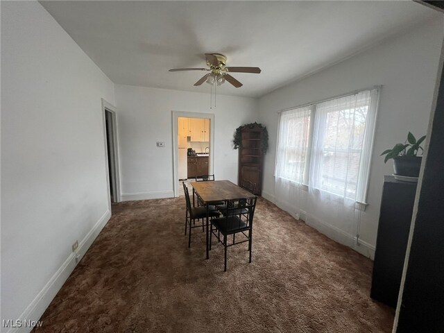 dining area with ceiling fan and dark colored carpet