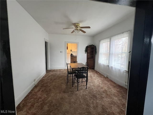 dining space featuring ceiling fan and dark colored carpet