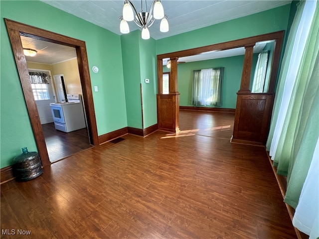 spare room with a wealth of natural light, dark hardwood / wood-style flooring, and decorative columns