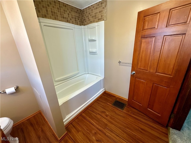 bathroom with hardwood / wood-style floors, shower / tub combination, and toilet