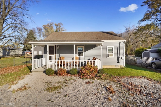 bungalow-style home featuring covered porch, a front lawn, and a storage shed