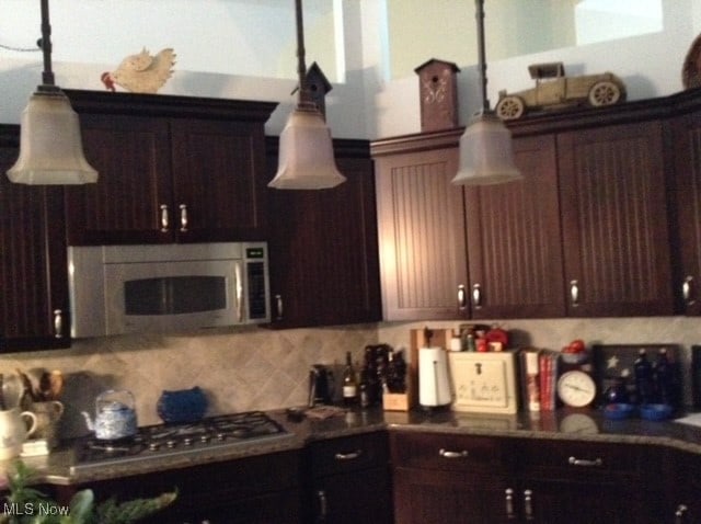 kitchen featuring dark brown cabinets, appliances with stainless steel finishes, and tasteful backsplash