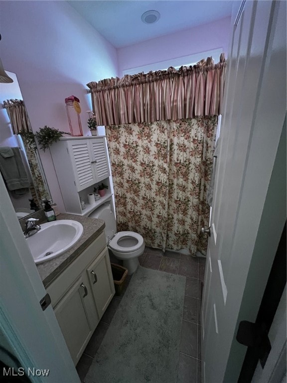 bathroom with toilet, vanity, and tile patterned floors