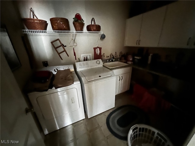 clothes washing area with cabinets, washer and clothes dryer, and sink