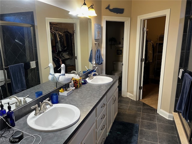 bathroom with tile patterned flooring, an enclosed shower, vanity, and toilet