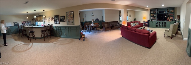 carpeted living room featuring bar area and built in features