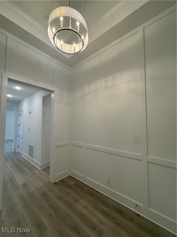 empty room featuring wood-type flooring and an inviting chandelier