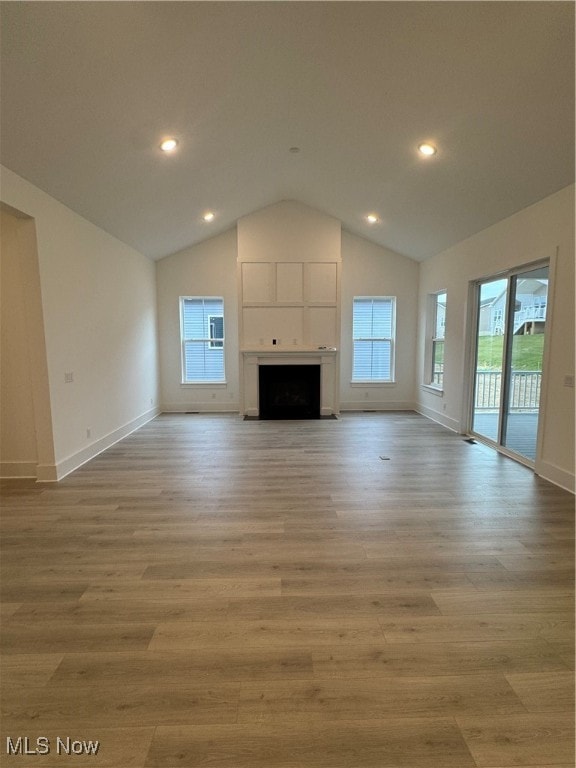 unfurnished living room with light wood-type flooring, lofted ceiling, and a fireplace