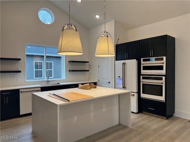 kitchen featuring sink, appliances with stainless steel finishes, decorative light fixtures, light hardwood / wood-style flooring, and a kitchen island