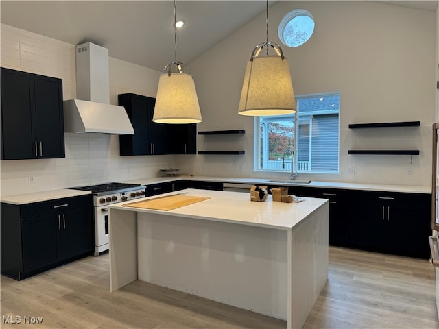 kitchen with a center island, high end range, hanging light fixtures, sink, and wall chimney range hood