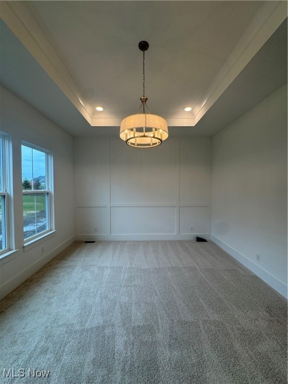 carpeted spare room featuring a tray ceiling