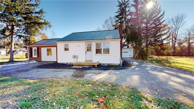 view of front of home featuring a front lawn, a garage, and an outbuilding