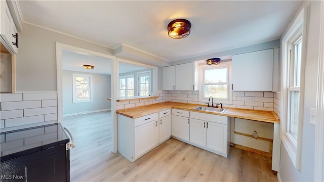 kitchen featuring white cabinets, butcher block counters, sink, and backsplash