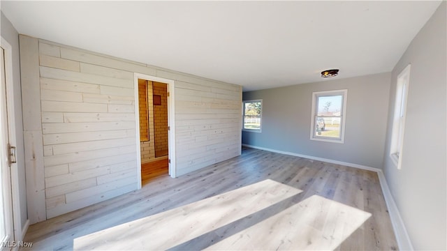 unfurnished room featuring light hardwood / wood-style floors and brick wall