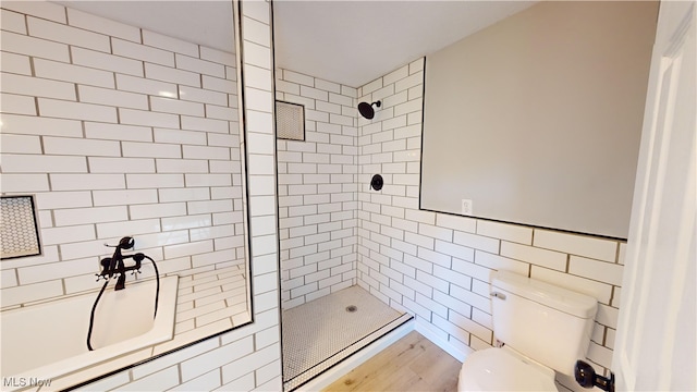 bathroom with tile walls, hardwood / wood-style floors, toilet, and a tile shower