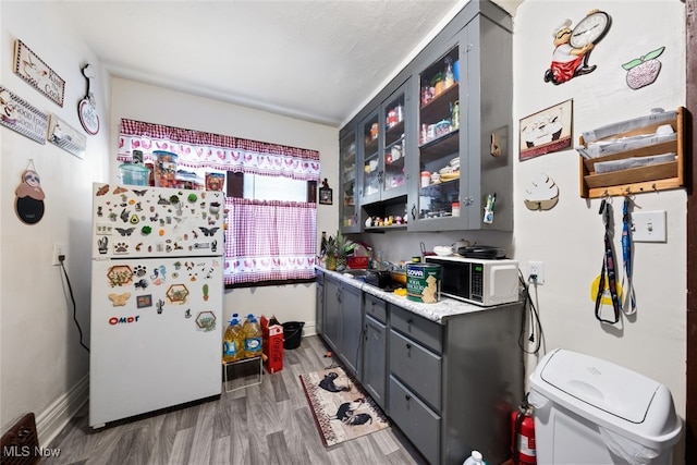 kitchen with wood-type flooring, sink, white appliances, and gray cabinetry