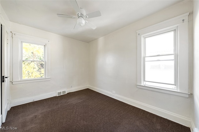 empty room with ceiling fan and dark colored carpet