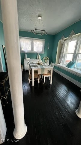 dining area featuring dark hardwood / wood-style floors, a healthy amount of sunlight, and decorative columns