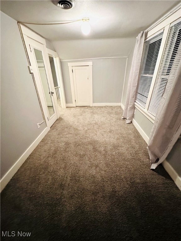 corridor with vaulted ceiling and light carpet